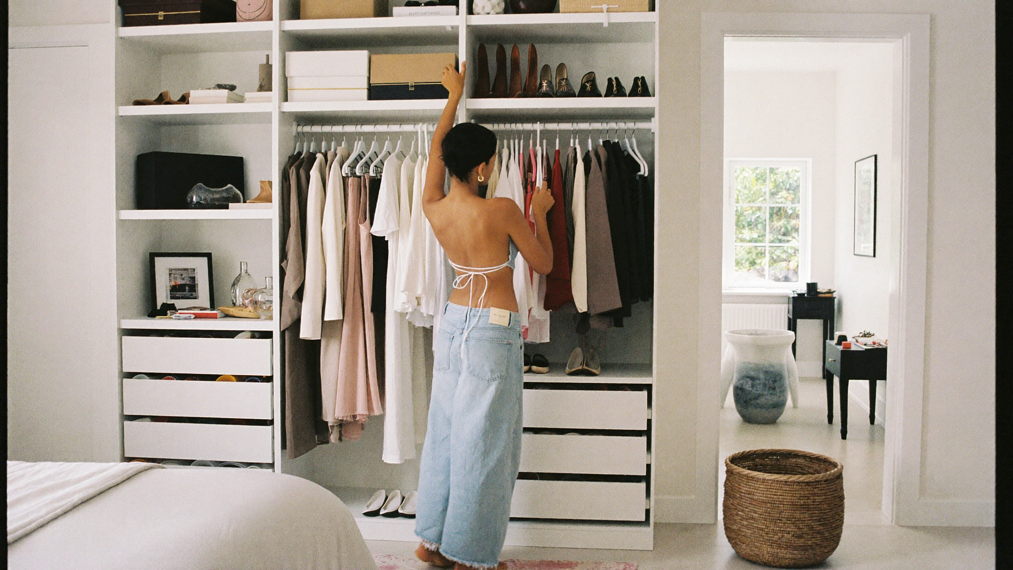 Woman choosing an outfit from a neutral-toned summer capsule wardrobe